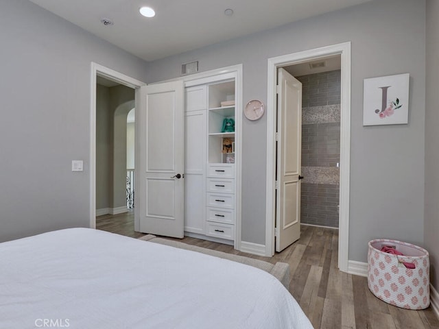1 Lennox Ct, Ladera Ranch, CA 92694 - bedroom featuring arched walkways, wood finished floors, baseboards, connected bathroom, and a closet