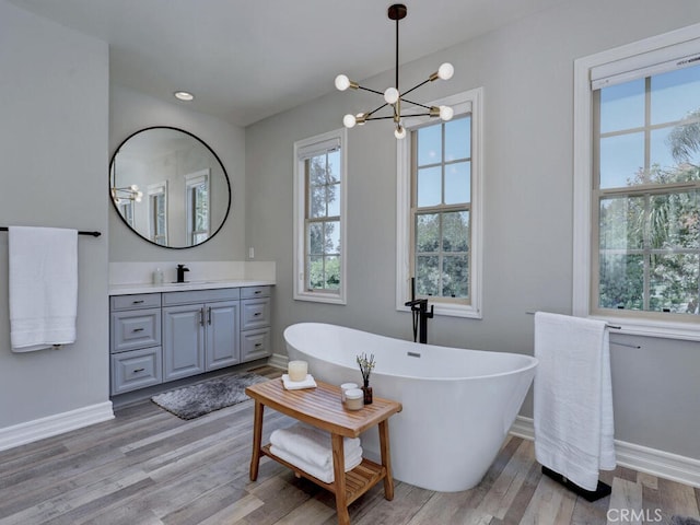 1 Lennox Ct, Ladera Ranch, CA 92694 - bathroom featuring baseboards, vanity, a chandelier, a freestanding tub, and wood finished floors