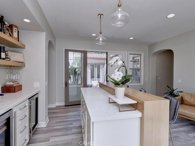 1 Lennox Ct, Ladera Ranch, CA 92694 - kitchen with arched walkways, beverage cooler, open shelves, light wood finished floors, and recessed lighting