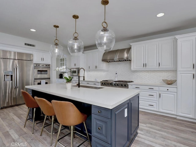 1 Lennox Ct, Ladera Ranch, CA 92694 - kitchen with built in appliances, wall chimney exhaust hood, a sink, white cabinetry, and light wood-type flooring