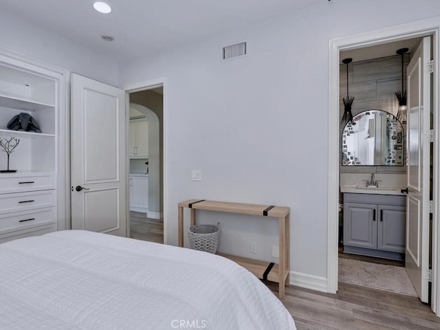 1 Lennox Ct, Ladera Ranch, CA 92694 - bedroom featuring wood finished floors, a sink, arched walkways, recessed lighting, and connected bathroom