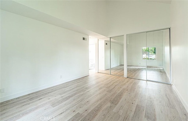 611 W 1st St Unit 101, Santa Ana, CA 92701 - unfurnished bedroom with multiple closets, light wood-type flooring, baseboards, and a towering ceiling