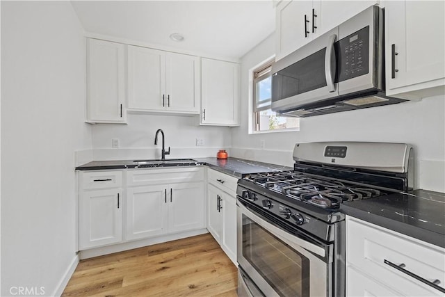 10931 S Burl Ave, Inglewood, CA 90304 - kitchen featuring stainless steel appliances, dark countertops, white cabinets, and light wood-style flooring
