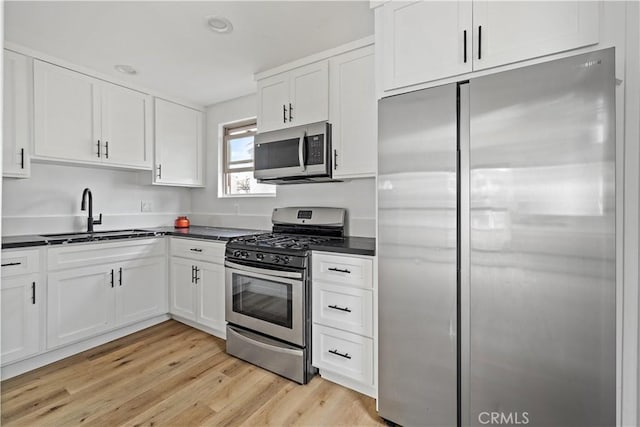 10931 S Burl Ave, Inglewood, CA 90304 - kitchen featuring stainless steel appliances, dark countertops, white cabinets, and light wood-style floors