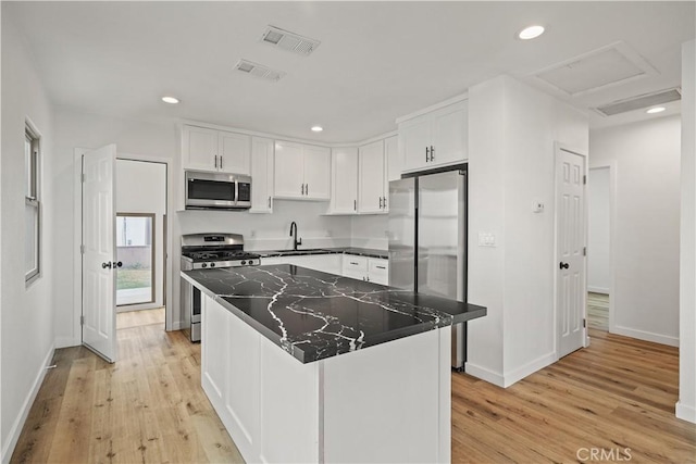 10931 S Burl Ave, Inglewood, CA 90304 - kitchen with stainless steel appliances, light wood finished floors, white cabinets, a kitchen island, and recessed lighting