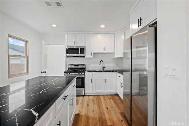 10931 S Burl Ave, Inglewood, CA 90304 - kitchen featuring stainless steel appliances, white cabinetry, dark stone countertops, light wood-style flooring, and recessed lighting