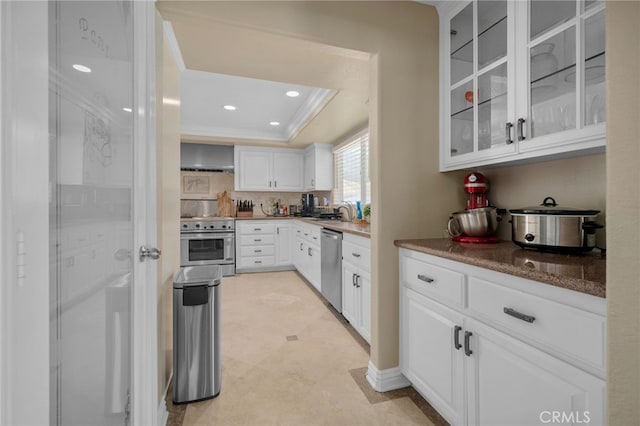 20605 Broadview Dr, Perris, CA 92570 - kitchen with appliances with stainless steel finishes, a tray ceiling, glass insert cabinets, white cabinetry, and wall chimney range hood