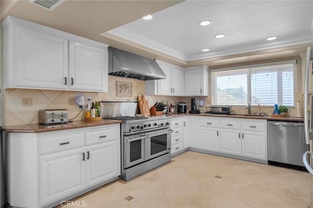 20605 Broadview Dr, Perris, CA 92570 - kitchen featuring wall chimney exhaust hood, stainless steel appliances, ornamental molding, white cabinetry, and dark stone countertops