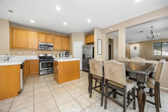 3762 Almansa Way, Perris, CA 92571 - kitchen with stainless steel appliances, tile countertops, a center island, a chandelier, and a sink