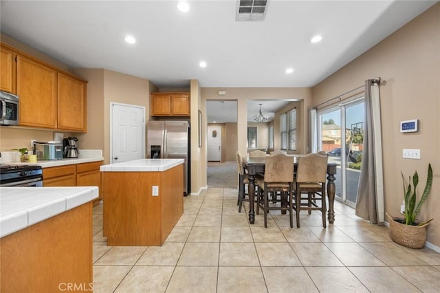 3762 Almansa Way, Perris, CA 92571 - kitchen with tile counters, a center island, appliances with stainless steel finishes, brown cabinets, and recessed lighting