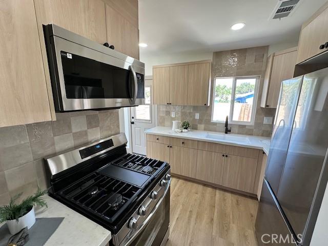 2510 Termino Ave, Long Beach, CA 90815 - kitchen featuring appliances with stainless steel finishes, light brown cabinetry, light countertops, tasteful backsplash, and recessed lighting
