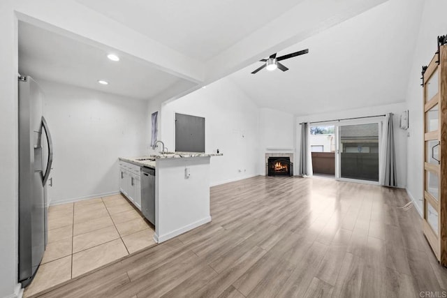 2920 Briarwood Rd Unit G12, Bonita, CA 91902 - kitchen with stainless steel appliances, a tiled fireplace, a barn door, recessed lighting, and light wood-style flooring