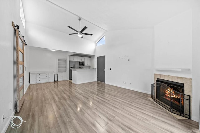 2920 Briarwood Rd Unit G12, Bonita, CA 91902 - unfurnished living room featuring a tile fireplace, high vaulted ceiling, a ceiling fan, light wood-type flooring, and baseboards