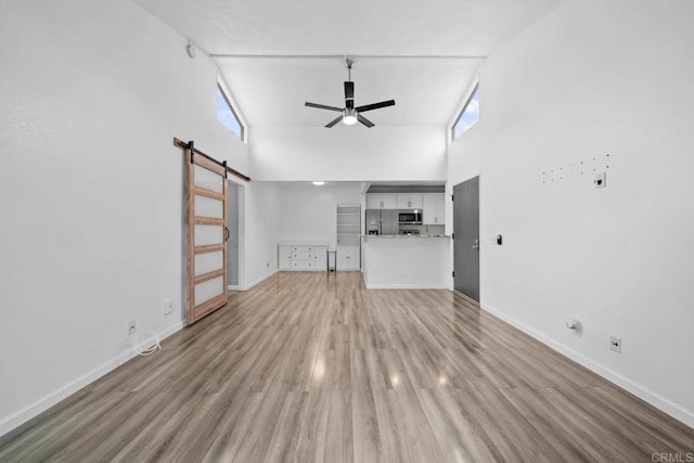 2920 Briarwood Rd Unit G12, Bonita, CA 91902 - unfurnished living room featuring a barn door, high vaulted ceiling, a ceiling fan, baseboards, and light wood-type flooring