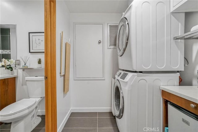 3839 Davana Rd, Sherman Oaks, CA 91423 - laundry area with stacked washing machine and dryer, dark tile patterned flooring, and baseboards