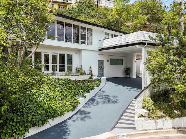 3839 Davana Rd, Sherman Oaks, CA 91423 - view of front facade with a carport, concrete driveway, stucco siding, a balcony, and french doors