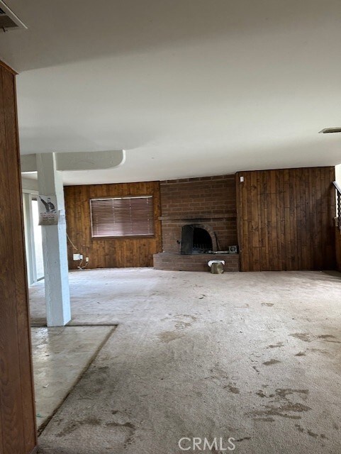 28450 6th St, Temecula, CA 92590 - unfurnished living room with carpet floors, wooden walls, and a fireplace