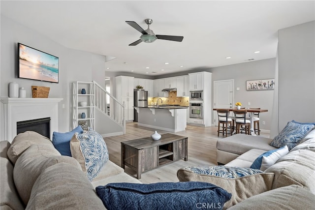 341 W Pebble Creek Ln, Orange, CA 92865 - living area with a ceiling fan, light wood-style flooring, stairway, recessed lighting, and a glass covered fireplace