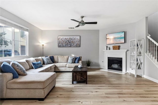 341 W Pebble Creek Ln, Orange, CA 92865 - living room featuring ceiling fan, light wood-style flooring, baseboards, a glass covered fireplace, and stairs