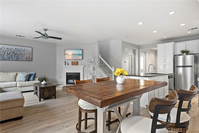 341 W Pebble Creek Ln, Orange, CA 92865 - dining space featuring light wood-style flooring, a glass covered fireplace, a ceiling fan, recessed lighting, and stairs