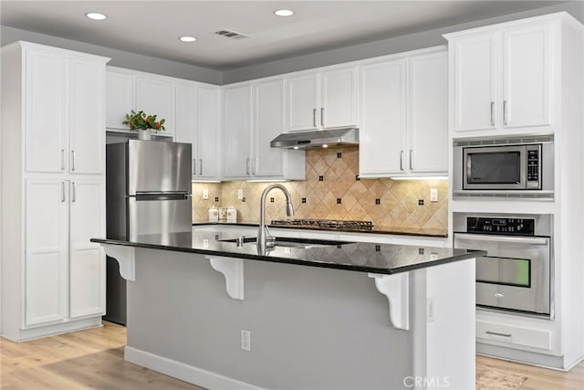 341 W Pebble Creek Ln, Orange, CA 92865 - kitchen with appliances with stainless steel finishes, under cabinet range hood, a kitchen breakfast bar, light wood finished floors, and white cabinetry