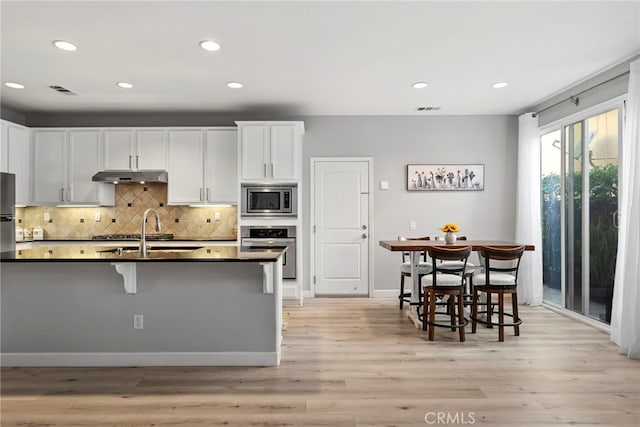 341 W Pebble Creek Ln, Orange, CA 92865 - kitchen with appliances with stainless steel finishes, a sink, under cabinet range hood, dark countertops, and a breakfast bar