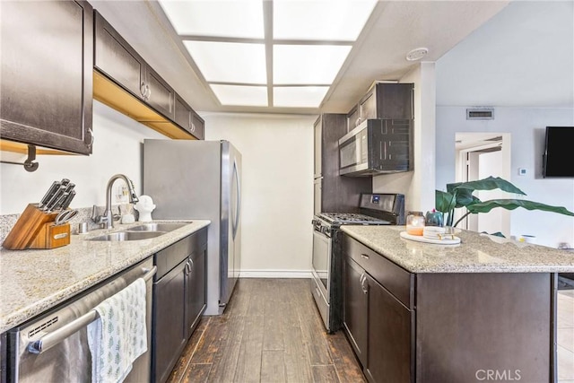 9038 Orion Ave Unit 107, North Hills, CA 91343 - kitchen with appliances with stainless steel finishes, a sink, dark brown cabinetry, light stone counters, and dark wood finished floors