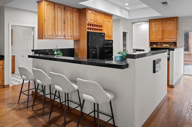 4036 Stonebridge Ln, Rancho Santa Fe, CA 92091 - kitchen featuring black appliances, a raised ceiling, dark countertops, a kitchen breakfast bar, and recessed lighting