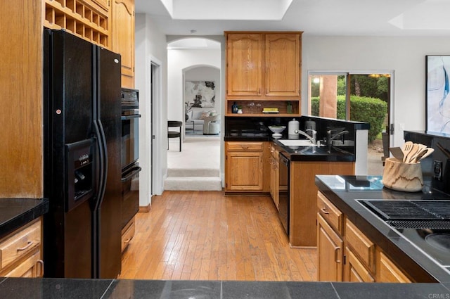 4036 Stonebridge Ln, Rancho Santa Fe, CA 92091 - kitchen with black appliances, a raised ceiling, light wood-style flooring, a peninsula, and arched walkways