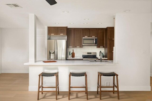 4158 Seri St, San Diego, CA 92117 - kitchen with appliances with stainless steel finishes, a peninsula, light countertops, a kitchen bar, and recessed lighting