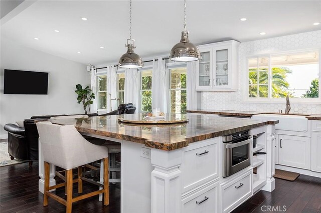 2212 Rim Rd, Duarte, CA 91008 - kitchen featuring dark wood finished floors, a kitchen island, white cabinetry, dark stone counters, and decorative backsplash