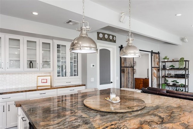 2212 Rim Rd, Duarte, CA 91008 - kitchen with a barn door, dark stone counters, white cabinets, glass insert cabinets, and recessed lighting