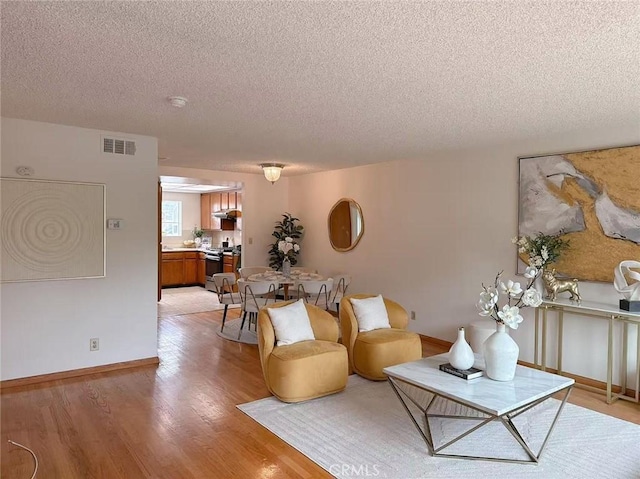 333 S Arroyo Dr Unit J, San Gabriel, CA 91776 - living room featuring a textured ceiling, light wood-style floors, and baseboards