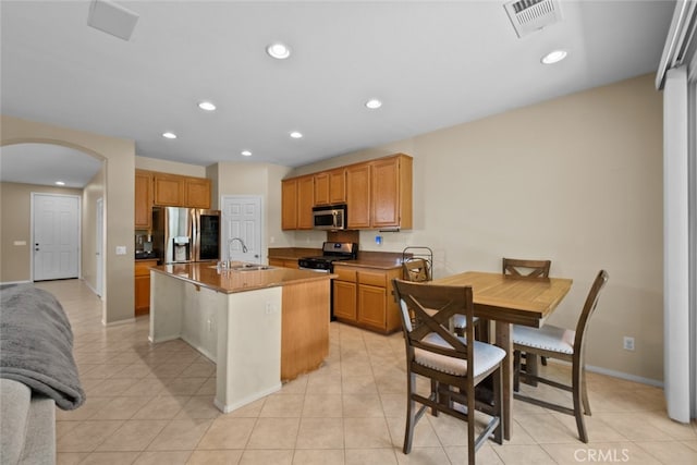 4616 W W Ave J2, Lancaster, CA 93536 - kitchen featuring appliances with stainless steel finishes, a sink, arched walkways, a center island with sink, and light tile patterned floors