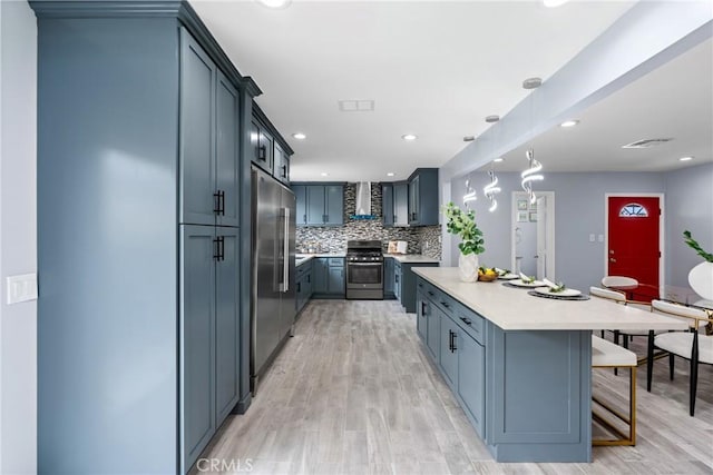7321 Eglise Ave, Pico Rivera, CA 90660 - kitchen with appliances with stainless steel finishes, light countertops, a kitchen bar, decorative backsplash, and light wood-style flooring