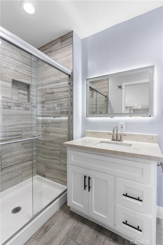 7321 Eglise Ave, Pico Rivera, CA 90660 - full bathroom featuring a stall shower, vanity, wood finished floors, and a textured wall