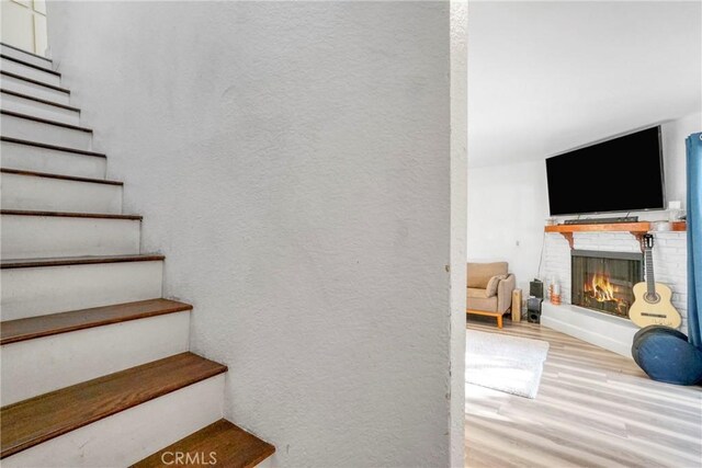 9414 Moonbeam Ave Unit 18, Panorama City, CA 91402 - stairs with wood finished floors, a brick fireplace, and a textured wall