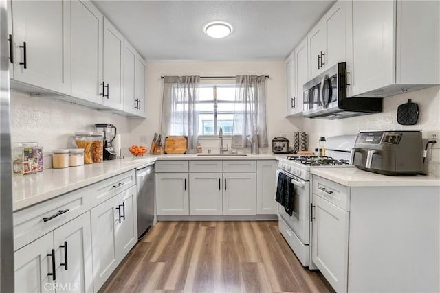 9414 Moonbeam Ave Unit 18, Panorama City, CA 91402 - kitchen featuring a sink, stainless steel appliances, light wood-type flooring, white cabinetry, and light countertops