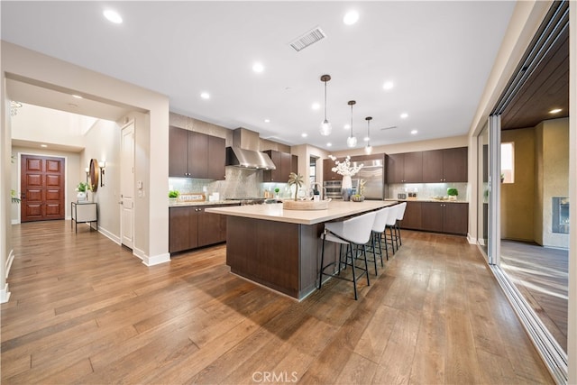 74 Gainsboro, Irvine, CA 92620 - kitchen with wall chimney range hood, light countertops, light wood finished floors, dark brown cabinetry, and recessed lighting