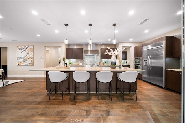 74 Gainsboro, Irvine, CA 92620 - kitchen featuring wall chimney range hood, appliances with stainless steel finishes, light countertops, a breakfast bar area, and recessed lighting
