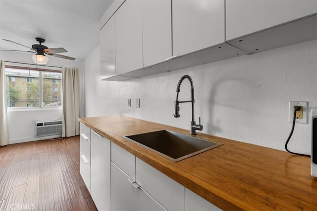 525 N Sycamore Unit 320, Los Angeles, CA 90036 - kitchen featuring a sink, a wall mounted AC, white cabinets, wood finished floors, and ceiling fan