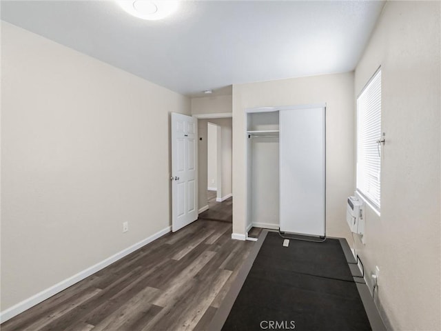 119 W 61st St, Los Angeles, CA 90003 - unfurnished bedroom featuring dark wood finished floors, baseboards, a closet, and a wall unit AC