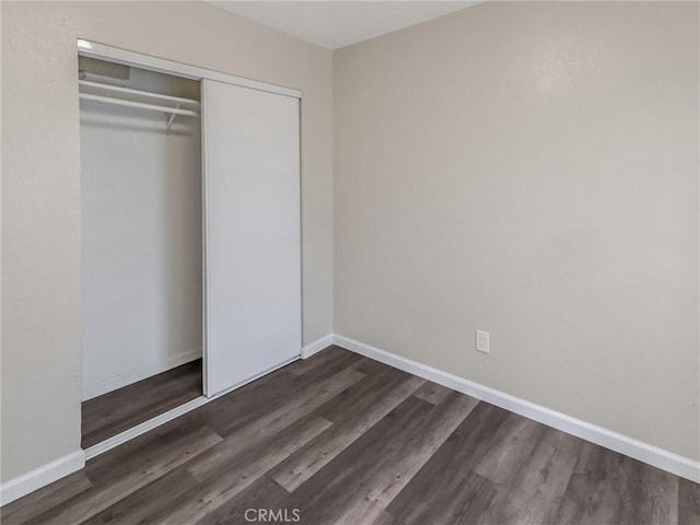 119 W 61st St, Los Angeles, CA 90003 - unfurnished bedroom with dark wood-style floors, a closet, and baseboards