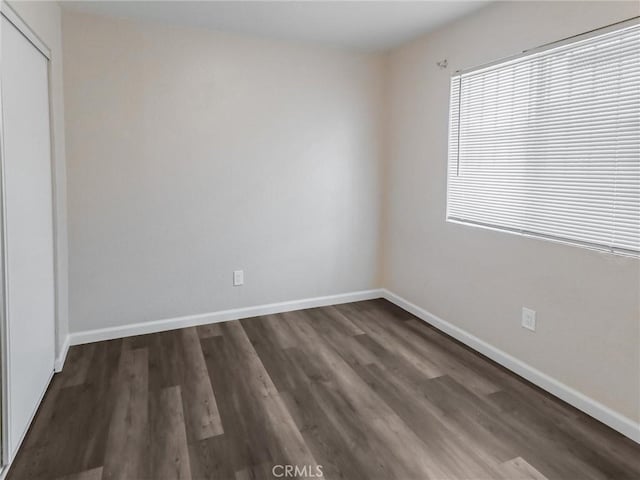 119 W 61st St, Los Angeles, CA 90003 - unfurnished bedroom with dark wood-style flooring, a closet, and baseboards