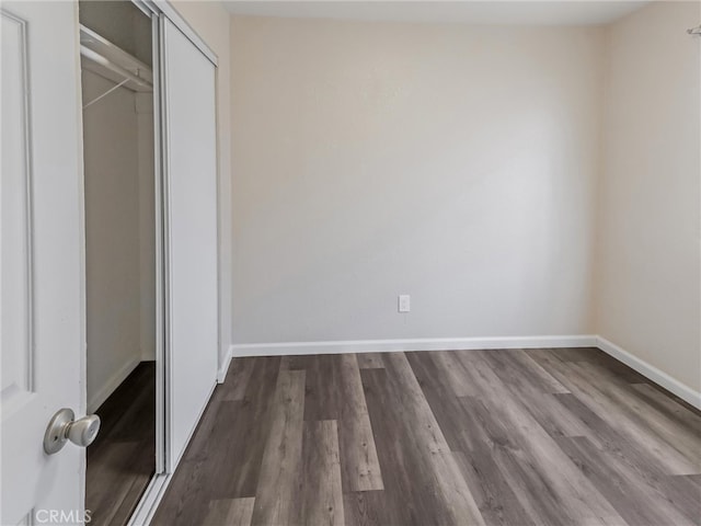 119 W 61st St, Los Angeles, CA 90003 - unfurnished bedroom featuring dark wood-style floors, a closet, and baseboards