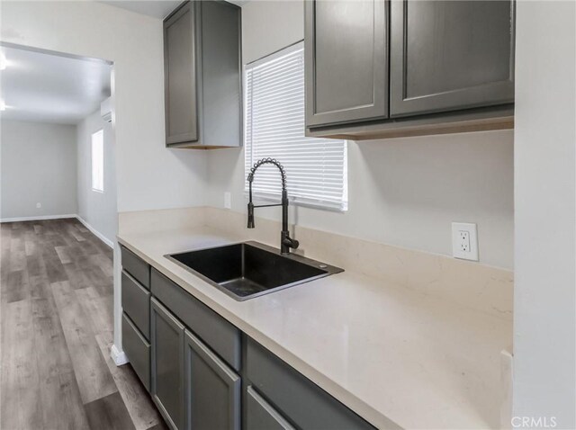 119 W 61st St, Los Angeles, CA 90003 - kitchen with gray cabinets, a sink, light countertops, and wood finished floors