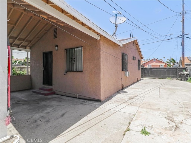 119 W 61st St, Los Angeles, CA 90003 - view of side of property featuring entry steps, stucco siding, a patio area, and cooling unit