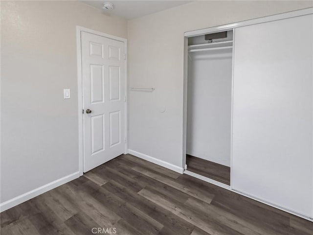 119 W 61st St, Los Angeles, CA 90003 - unfurnished bedroom with dark wood-style flooring, a closet, and baseboards