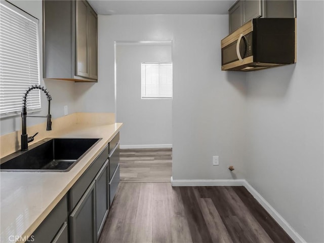 119 W 61st St, Los Angeles, CA 90003 - kitchen with gray cabinets, stainless steel microwave, a sink, dark wood-style flooring, and light countertops