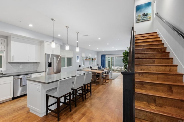 867 Wilbur Ave, San Diego, CA 92109 - kitchen featuring appliances with stainless steel finishes, dark countertops, white cabinets, a kitchen bar, and recessed lighting